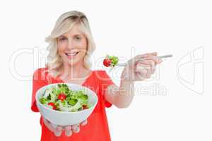 White bowl of vegetable salad held by a young blonde woman