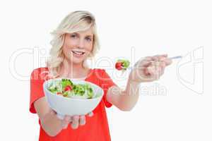 Young blonde woman holding a bowl of fresh salad