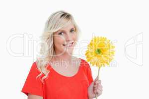 Smiling young woman holding a yellow flower