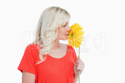 Young blonde woman smelling a yellow flower