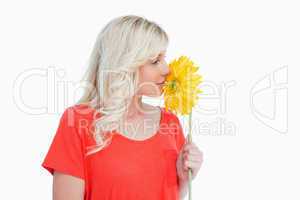 Young blonde woman smelling a yellow flower
