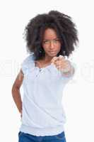 Young serious woman with curly hairstyle pointing her finger