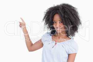 Smiling young woman pointing back side by finger