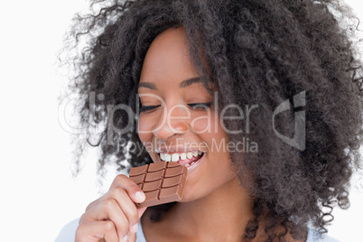 Young woman eating a delicious piece of chocolate bar