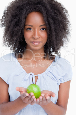 Young curly woman holding a green apple in her hands