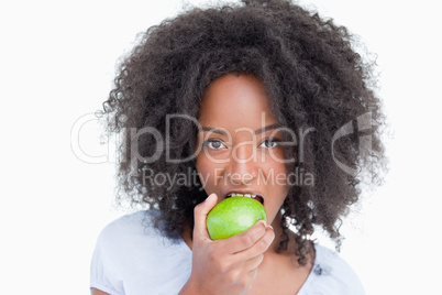 Young woman looking at the camera and eating a green apple
