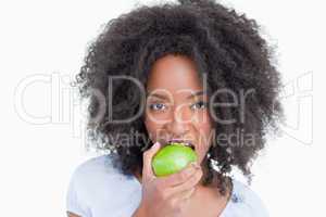 Young woman looking at the camera and eating a green apple