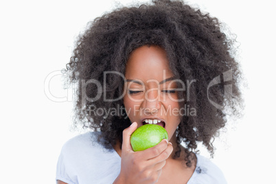 Young woman closing her eyes while eating a green apple