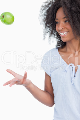 Young woman throwing a green apple in the air