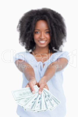 A fan of dollar notes held by a smiling woman with curly hair