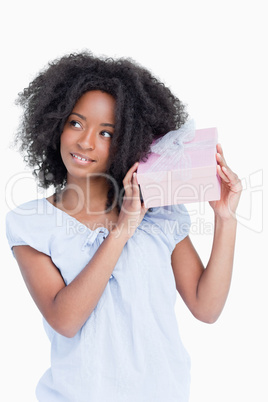 Young woman looking on the side while shaking a gift