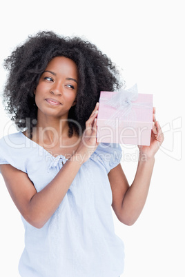 Young woman shaking her gift in order to guess what it is