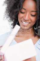 Young smiling woman joyfully opening her birthday gift