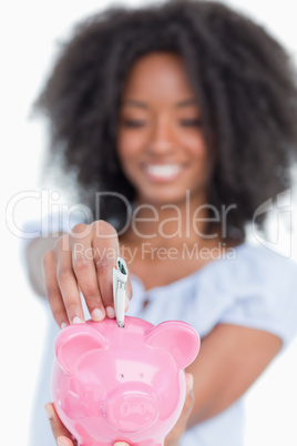 Piggy bank getting dollar notes while held by a young woman