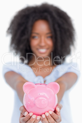 Pink piggy bank held by a young smiling woman with curly hair