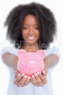 Pink piggy bank held by a woman in front of the camera