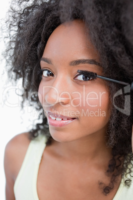 Smiling young woman applying black mascara