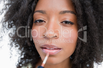 Young woman using a lip gloss applicator to make-up