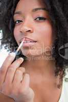 Young woman applying gloss in a concentrated way
