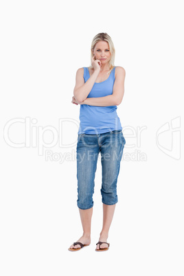 Serious blonde woman standing up with finger on her cheek