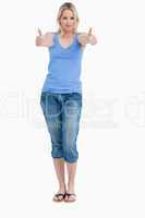 Blonde woman standing upright while placing her thumbs up