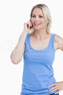 Smiling blonde woman using a mobile phone with a hand on her hip