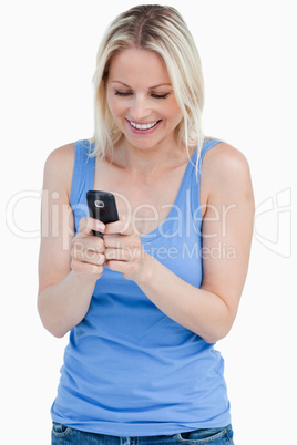 Smiling blonde woman sending a text with her cellphone