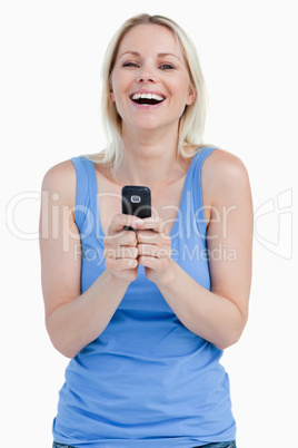 Blonde woman laughing while sending a text with her mobile phone