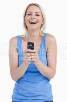 Blonde woman laughing while sending a text with her mobile phone