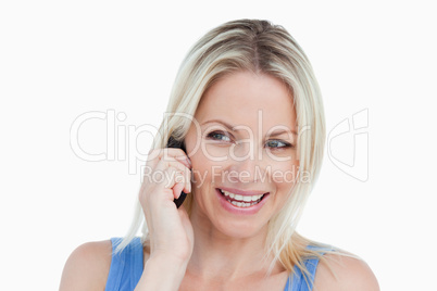 Smiling blonde woman looking on the side while on the phone