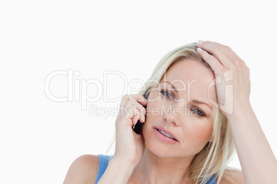 Serious blonde woman calling while placing her hand on her head