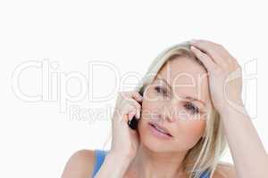 Serious blonde woman calling while placing her hand on her head