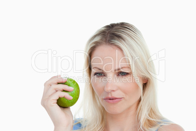 Thoughtful blonde woman holding a green apple