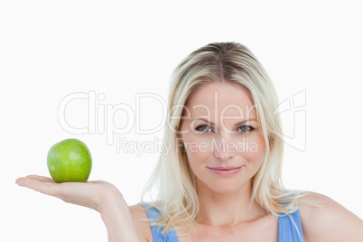 Blonde woman holding an apple in her hand palm