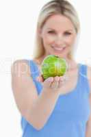 Delicious green apple held by a smiling blonde woman