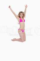 Attractive blonde woman wearing a pink swimsuit while jumping