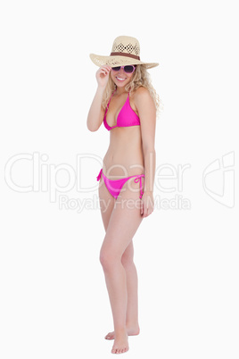 Young woman standing upright while holding her hat brim