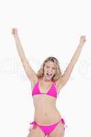 Young attractive woman in beachwear raising her arms above the h