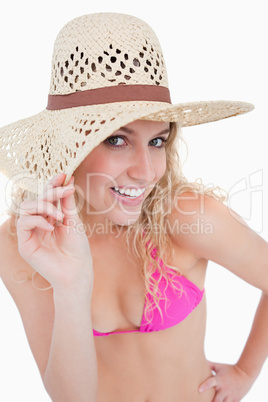 Young blonde woman looking at the camera while holding her hat b