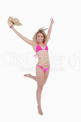 Smiling young blonde woman raising her arms while holding her ha