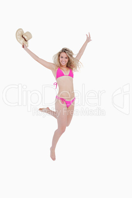 Smiling young woman raising her arms while flicking her leg back