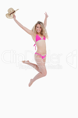 Young beautiful woman holding her hat in her raised arm