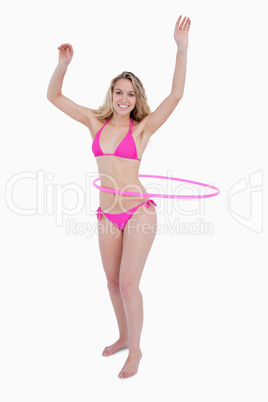 Beautiful teenager in beachwear playing hula-hoop