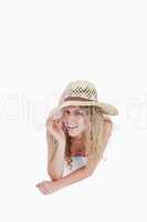 Smiling teenager lying down while holding her hat brim