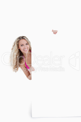 Smiling teenager hiding her body behind a blank poster