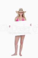 Smiling teenager in a pink swimsuit holding a blank poster