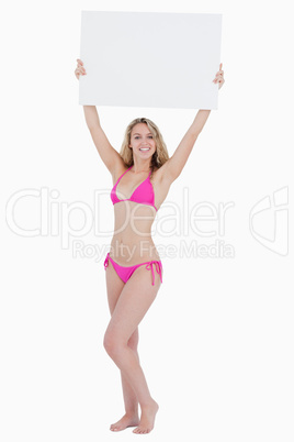 Young blonde woman raising a blank poster above her head