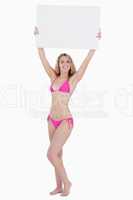 Young blonde woman raising a blank poster above her head