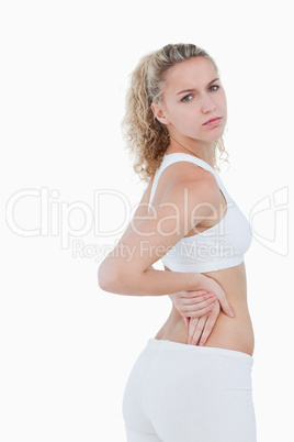 Young serious woman showing a pain in the back