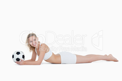 Young smiling woman lying down while holding a football